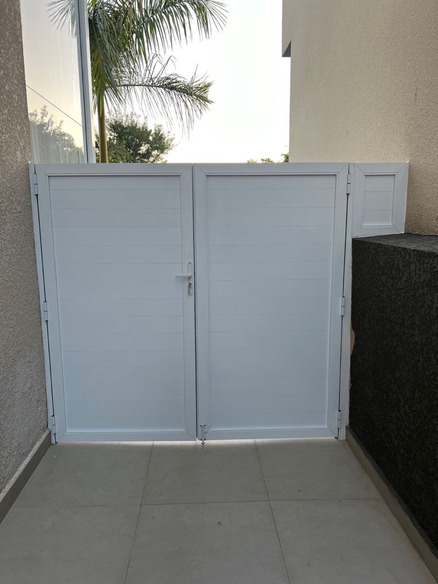 Porta de alumínio de duas folhas com lambril branco, instalada em área externa. Obra da VitraAlu em Alphaville, Barueri.