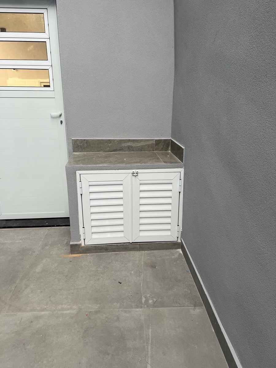 Abrigo de pia em alumínio branco com portas em veneziana, instalado em área de serviço externa. Obra da VitraAlu em Barra Funda, São Paulo.