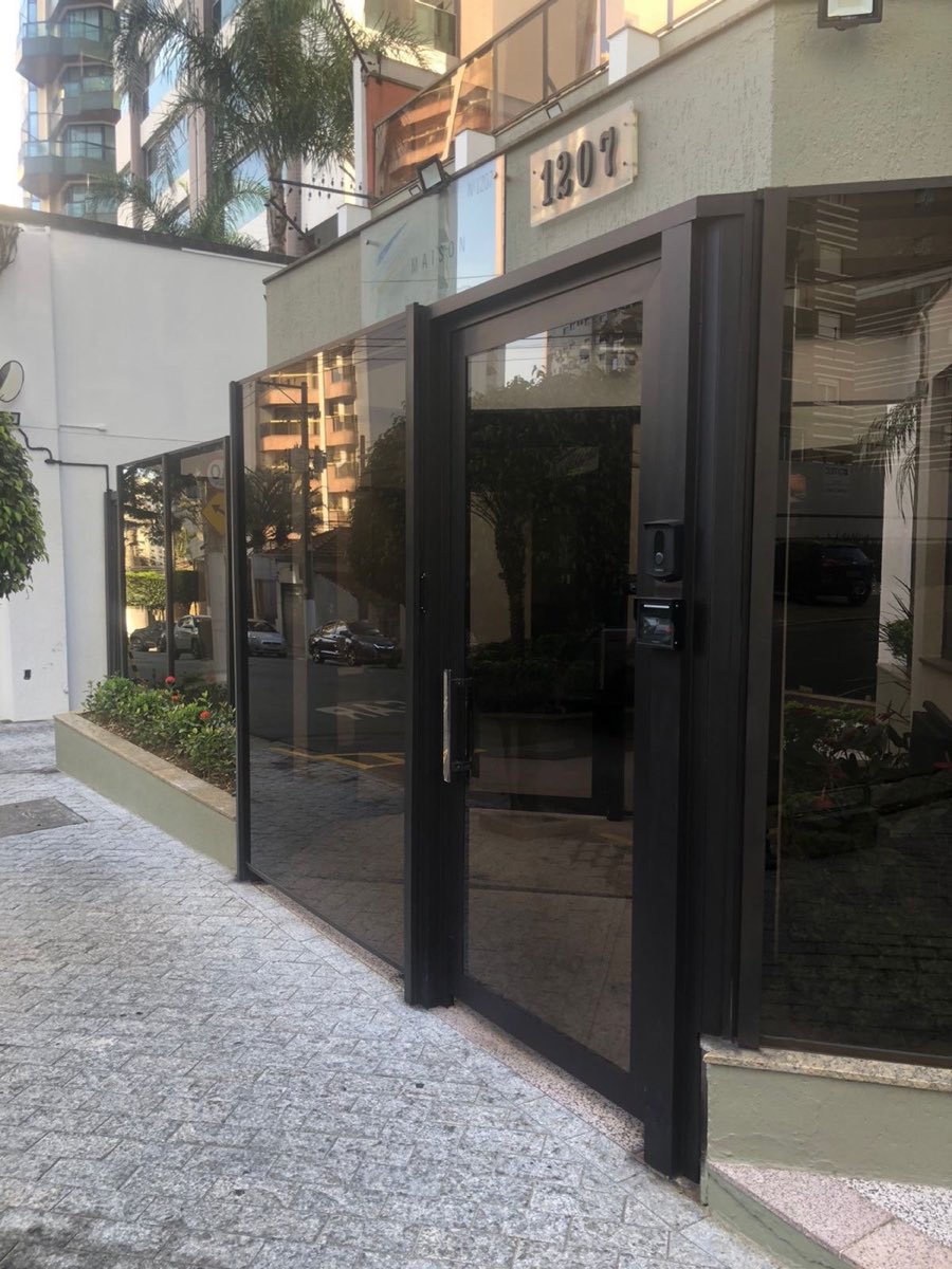 Porta de vidro emoldurada por esquadria de alumínio preto na entrada. Obra da VitraAlu em Anália Franco, São Paulo.