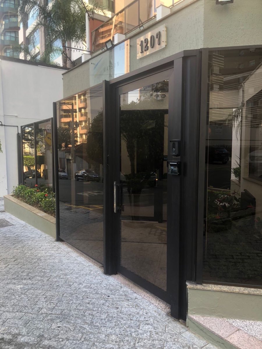 Entrada de edifício envidraçada com esquadrias de alumínio preto. Obra da VitraAlu em Anália Franco, São Paulo.
