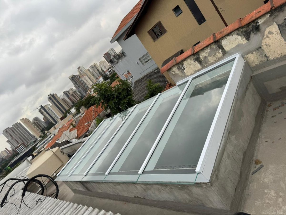 Vista lateral de cobertura de vidro com perfis de alumínio branco. Obra da VitraAlu em Pinheiros, São Paulo.