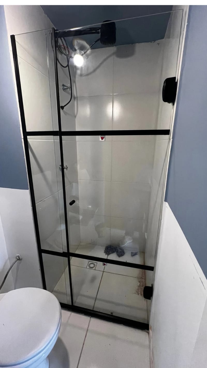 Box frontal em vidro incolor com perfil de alumínio preto, instalado em banheiro com parede azul.