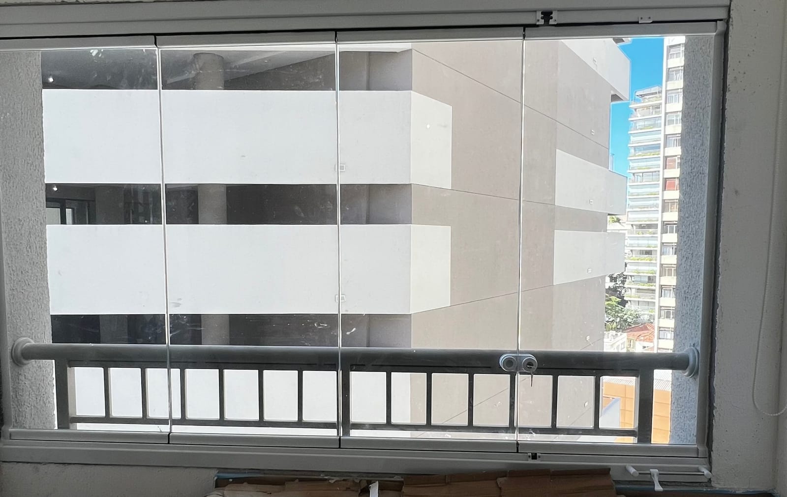 Sacada de apartamento fechada com envidraçamento de vidro em esquadria de alumínio branco, com vista para o prédio vizinho. Obra da VitraAlu em Pinheiros, São Paulo.