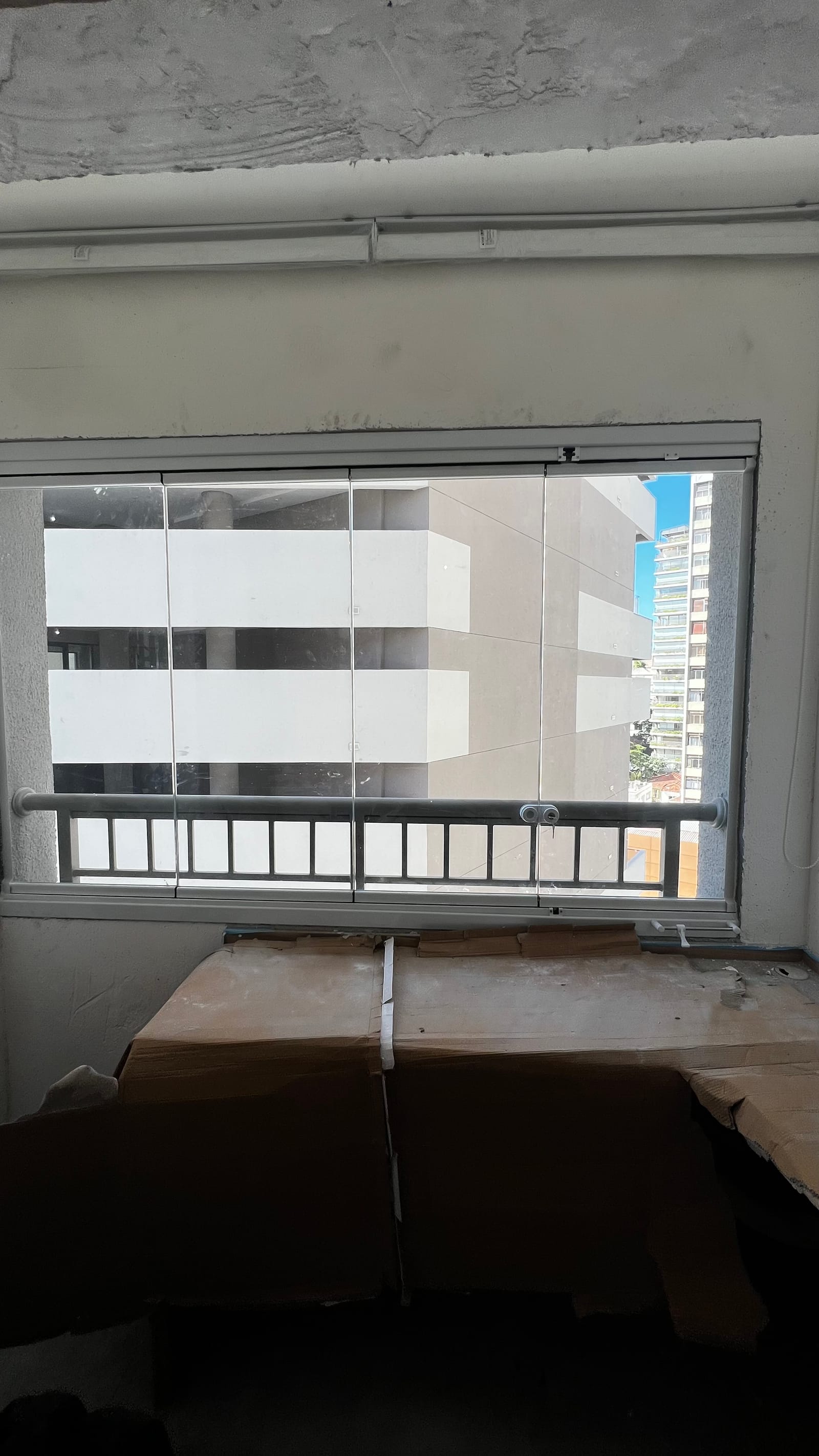 Sacada de apartamento fechada com envidraçamento de vidro em esquadria de alumínio branco, vista de dentro do ambiente. Obra da VitraAlu em Pinheiros, São Paulo.
